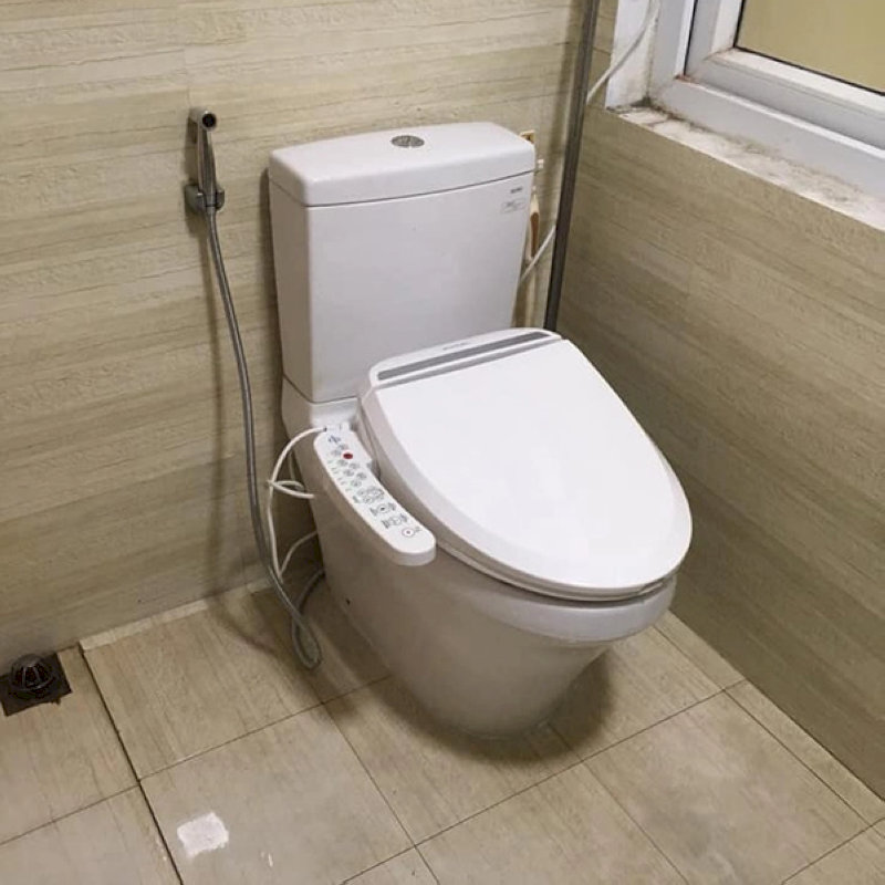 Bồn cầu có nắp rửa thông minh gắn điều khiển bên cạnh, đặt gần vòi xịt và ổ điện trong toilet hiện đại