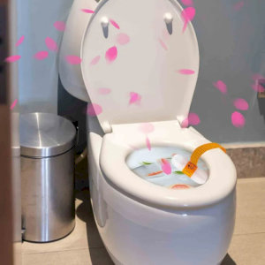 Bồn cầu màu trắng với nắp mở, được trang trí hoa anh đào và cá vàng, tạo cảm giác độc đáo.