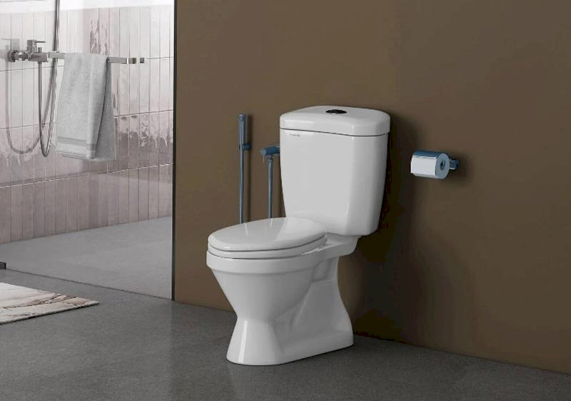 Bồn cầu Viglacera V39M màu trắng, thiết kế liền khối hiện đại, đặt trong phòng tắm với vòi sen, khăn tắm và giấy vệ sinh.