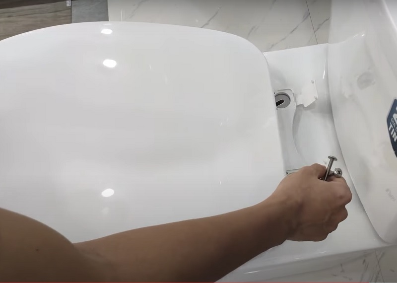 Căn chỉnh các lỗ của nắp bồn cầu mới cho vừa vặn với các lỗ bắt vít trên thân
