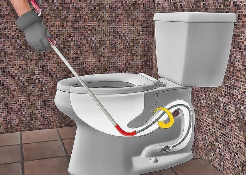  Kỹ thuật viên dùng lò xo thông tắc linh hoạt để loại bỏ vật cản trong đường ống bồn cầu sứ